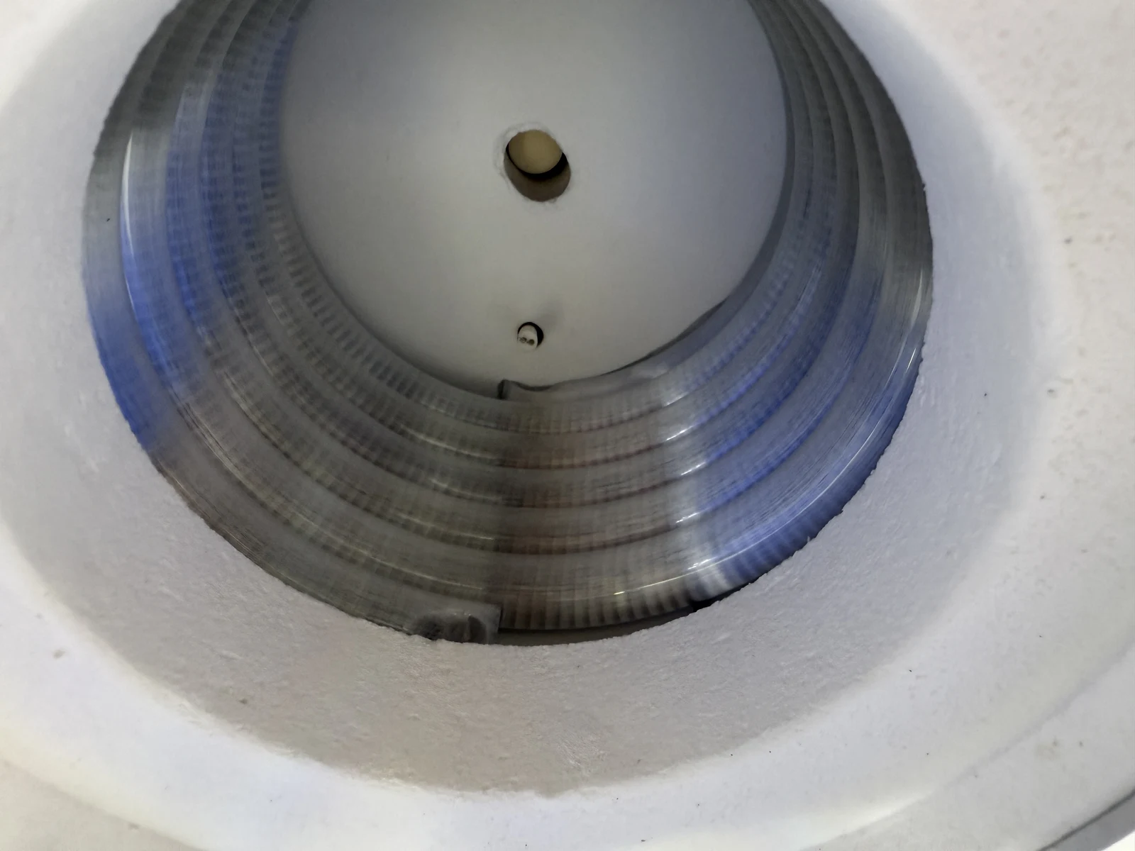 Interior of a dental press furnace showing the cylindrical heated chamber and temperature-sensor access