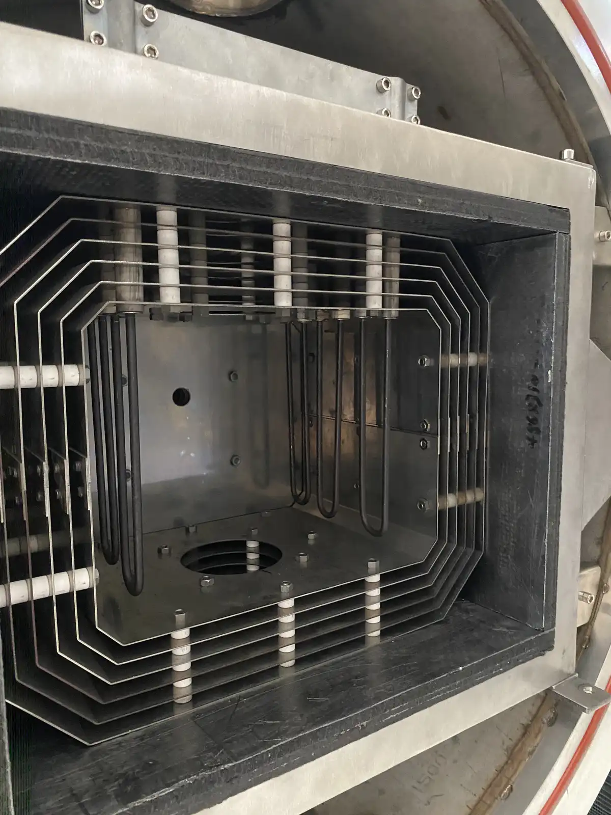 Internal hot zone of a vacuum hot press furnace showing layered radiation shielding, heating elements and tooling clearance